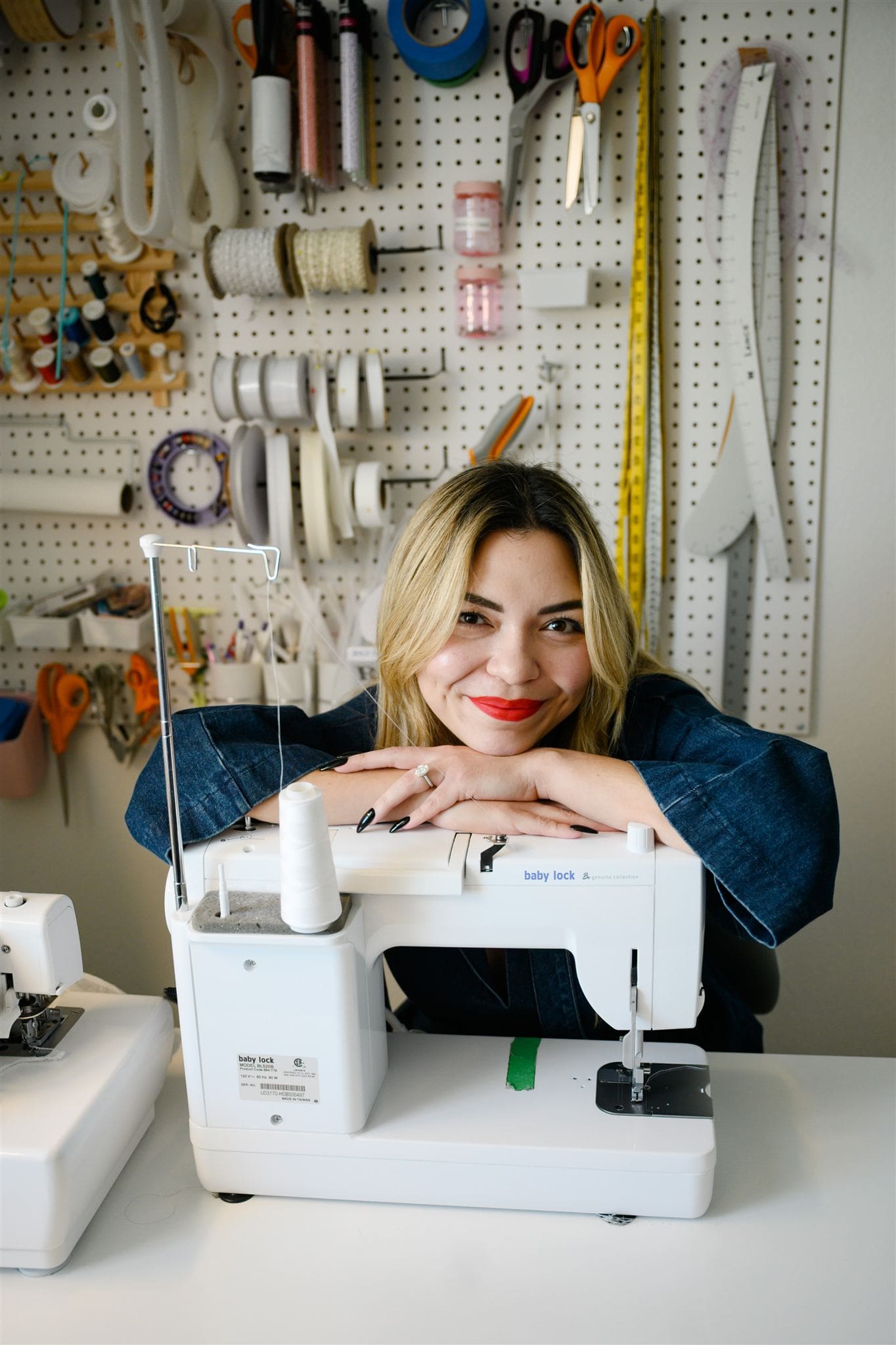 Alex, a bridal alterations expert in Austin, smiling with sewing machine
