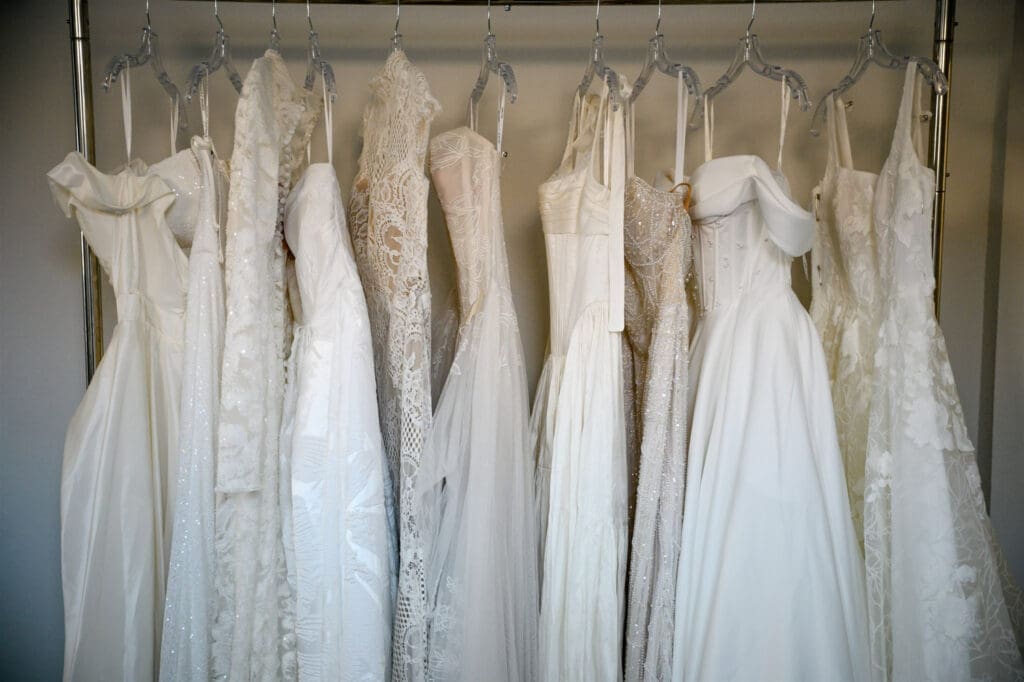 Wedding dresses hanging on a rack in a bridal alterations studio.