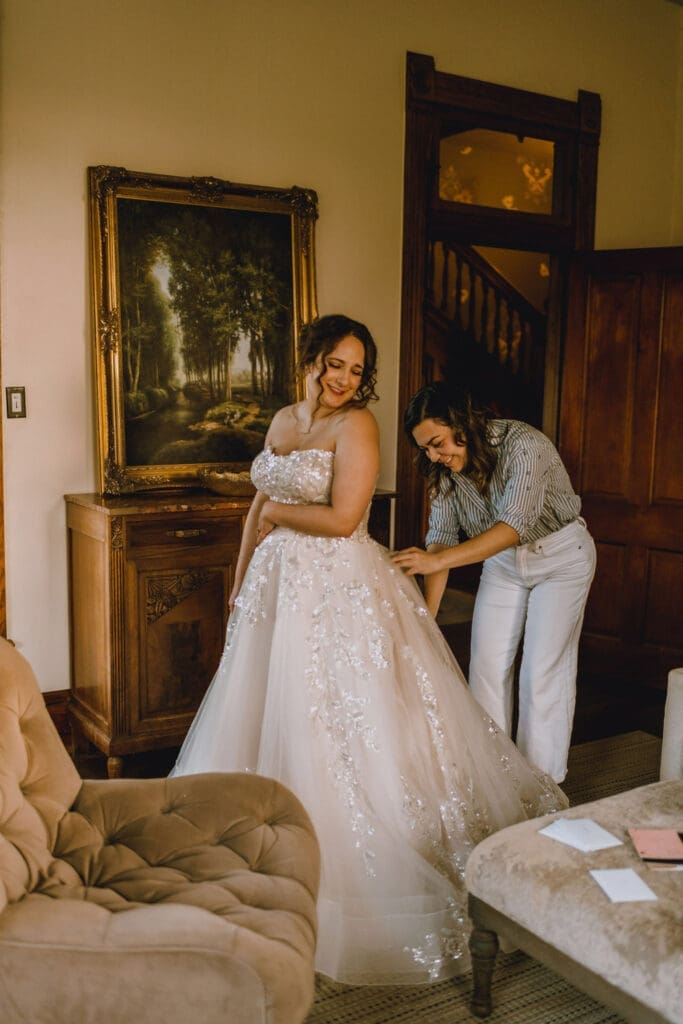 Seamstress pinning a bride’s wedding gown during an alterations fitting.
